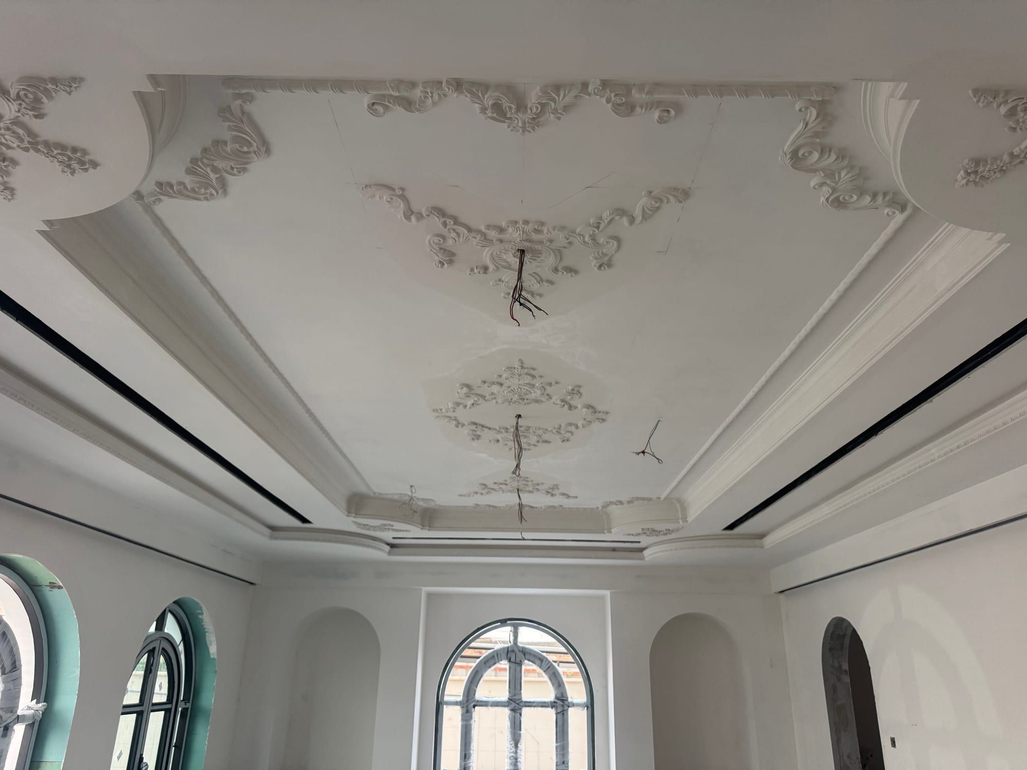 Ornamental plasterwork fixed to a stepped ceiling above a row of arched windows